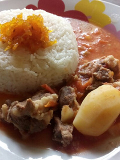 A picture of Rice and mutton soup curry with mango pickle.