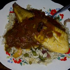A picture of Vegetable rice with fish fillet topped with tomato sauce.