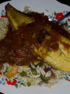 A picture of Vegetable rice with fish fillet topped with tomato sauce.