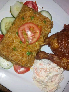 A picture of Jollof rice,coleslaw and grilled chicken.