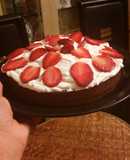 Moist chocolate cake topped with whipped cream and strawberries