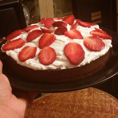 A picture of Moist chocolate cake topped with whipped cream and strawberries.
