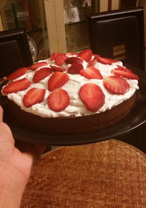 A picture of Moist chocolate cake topped with whipped cream and strawberries.