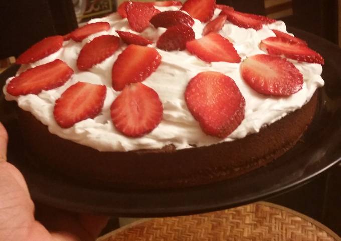 Moist chocolate cake topped with whipped cream and strawberries