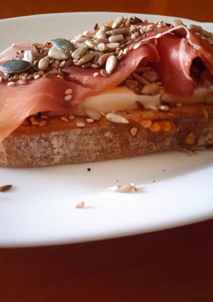 Una foto de Tostada con queso fresco, semillas y jamón