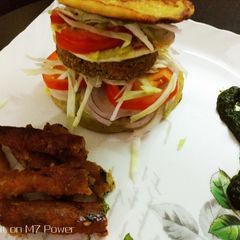A picture of Semolina Avocado cake  veg burger with dal tikki  and stick.