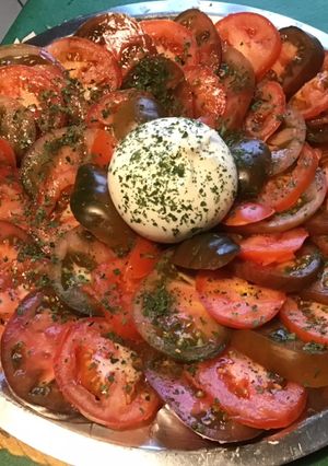 Une photo de Salade de tomates bicolores à la burrata di buffala et persil haché