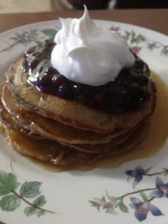 A picture of Cinnamon Clove Pancakes with Blueberry Sauce and Whipped Cream.