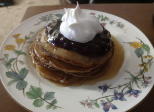A picture of Cinnamon Clove Pancakes with Blueberry Sauce and Whipped Cream.