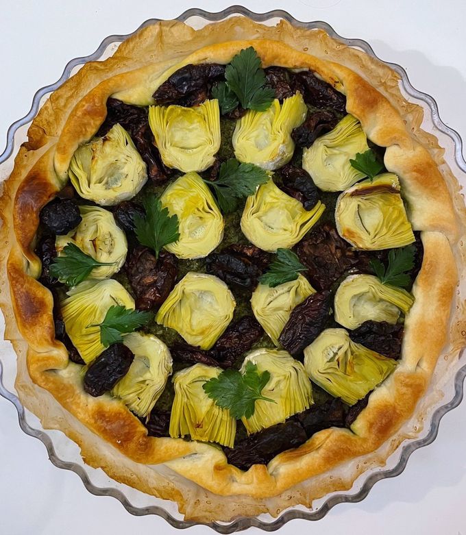 Une photo de La tarte salée au pesto, tomates séchées et cœurs d’artichauts. 🍅