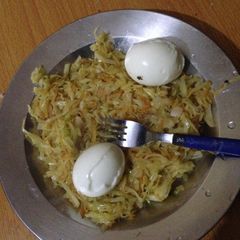 A picture of Steamed cabbage and carrots served with hard boiled eggs.