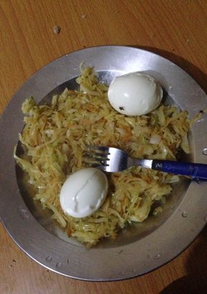 A picture of Steamed cabbage and carrots served with hard boiled eggs.