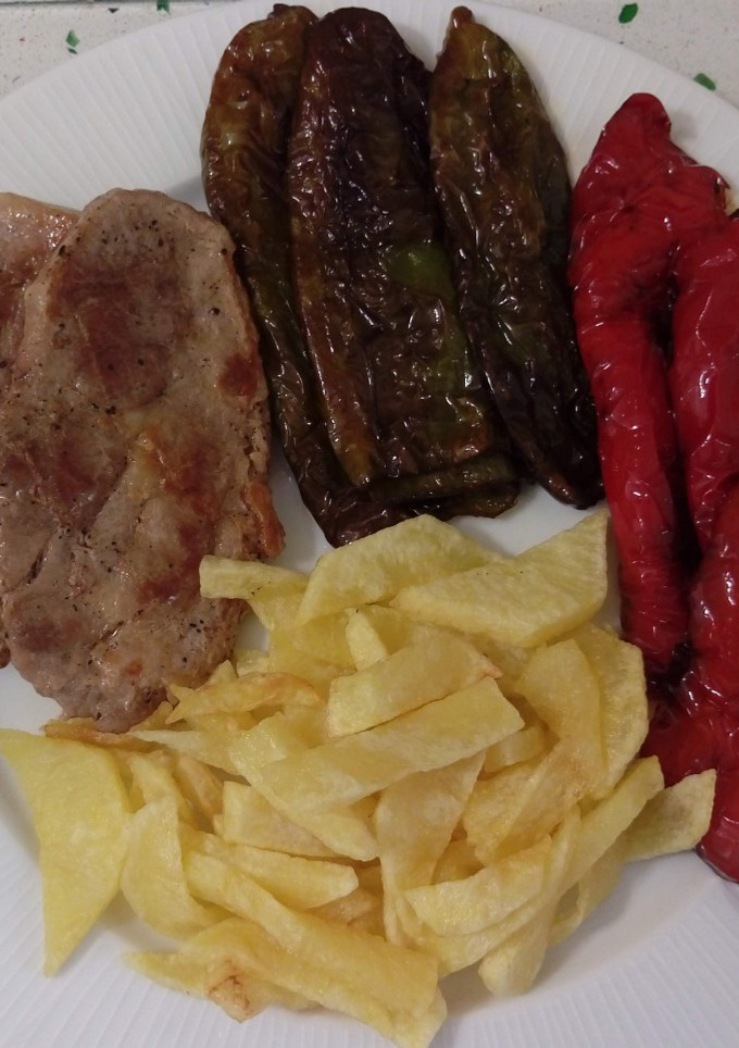 Una foto de Chuletas de cabeza de cerdo con patatas y pimientos fritos