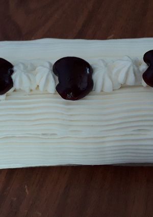 Una foto de Pionono relleno de dulce de leche, decorado con crema chantilly