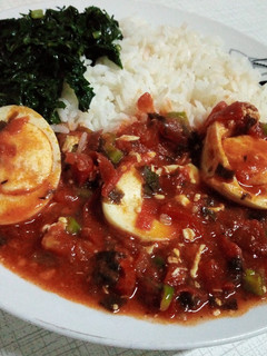 A picture of Egg curry served with rice and spinach.