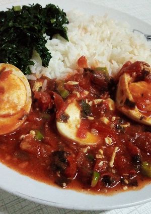 A picture of Egg curry served with rice and spinach.
