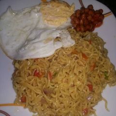 A picture of Jollof Noodles; Sunny Side up & Baked Beans.