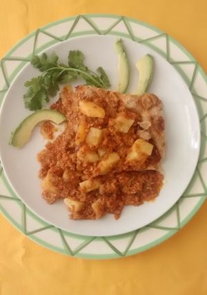 Una foto de Chorizo con papas en salsa verde sobre una cama de chicharrón