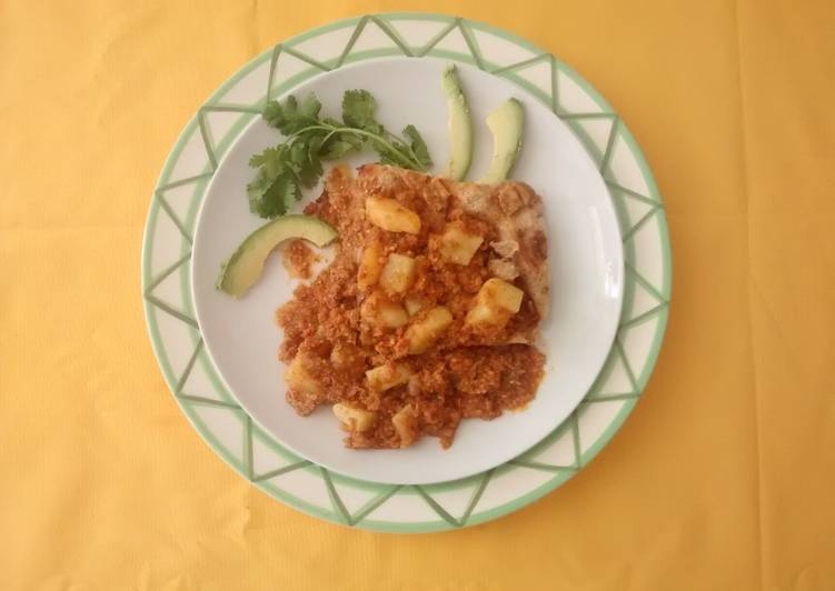 Chorizo con papas en salsa verde sobre una cama de chicharrón