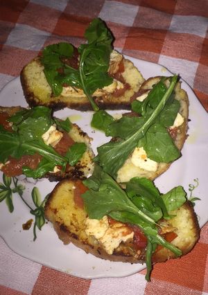 Una foto de Bruschetas de tomate y ricota al romero, con un toque de rúcula