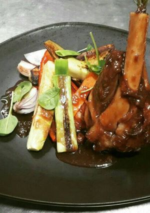 A picture of Duck drum in demi-glace and grilled vegetables.