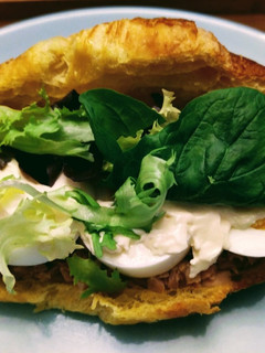 Una foto de Croissant con atún, huevo y lechuga variada
