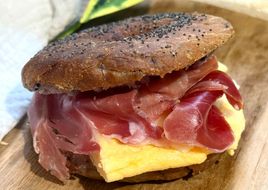 Bagel de arándanos con tortilla francesa, jamón serrano y queso