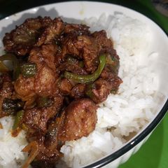 A picture of Onion and green pepper beef stir fry with rice.