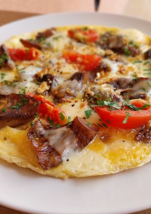 Una foto de Tortilla abierta de rovellons, emmental y tomate