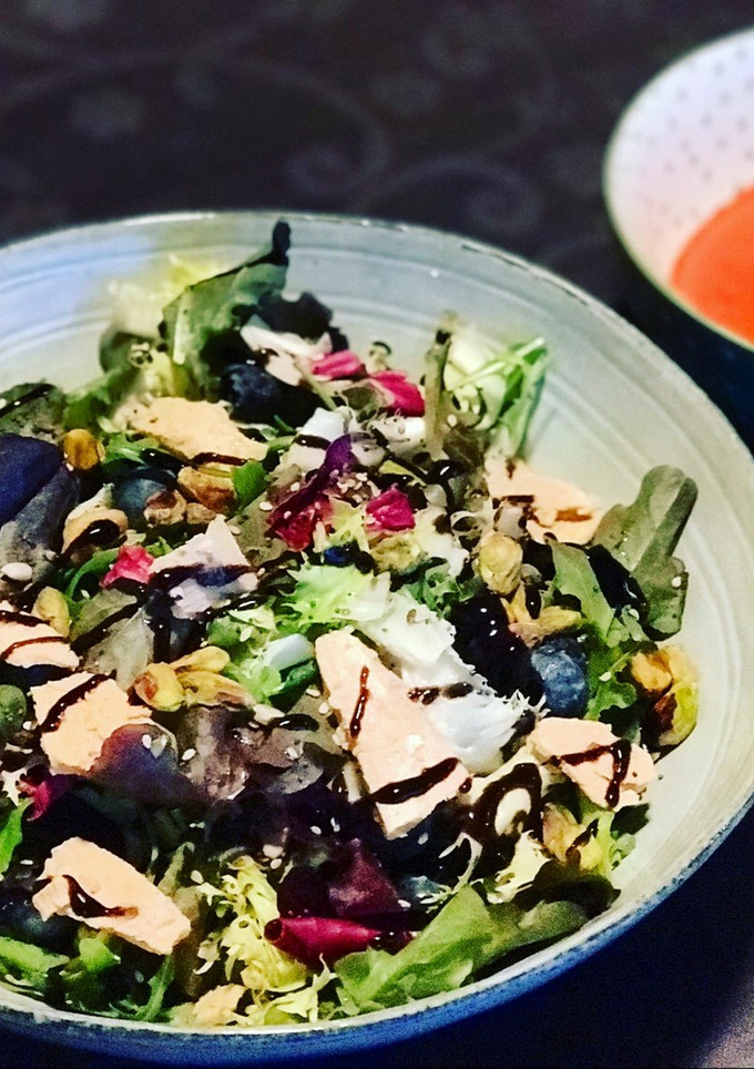 Una foto de Mezclum de lechugas con arándanos, foei, pistachos y semillas con vinagreta de frambuesa