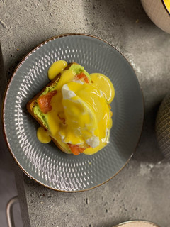 A picture of Breakfast poached egg toast with avocado cream, salmon and hollandaise.