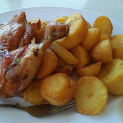 A picture of Garnished rosemary potatoes and fried chicken.