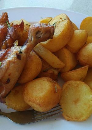A picture of Garnished rosemary potatoes and fried chicken.