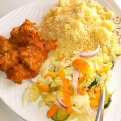 A picture of Couscous, chicken sauce and stir fried cabbage.