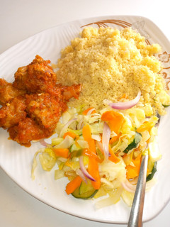 A picture of Couscous, chicken sauce and stir fried cabbage.