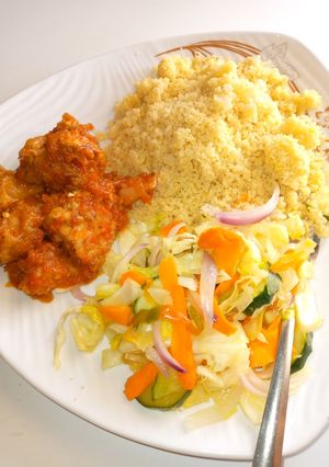 A picture of Couscous, chicken sauce and stir fried cabbage.