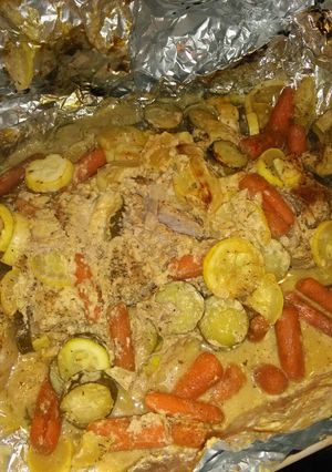 A picture of Foil wrapped honey mustard pork loin with zucchini, squash, and baby carrots.