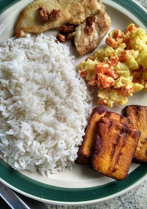 Una foto de Pollo al ajillo con arroz, ensalada y tajada