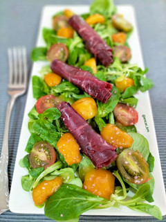 Una foto de Ensalada de canónigos con cecina y nísperos