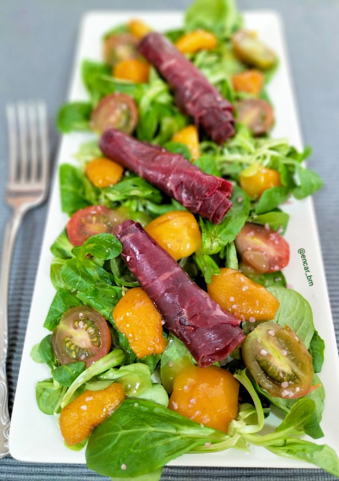 Una foto de Ensalada de canónigos con cecina y nísperos