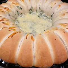 A picture of Spinach and artichoke dip with rolls.