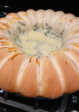 A picture of Spinach and artichoke dip with rolls.