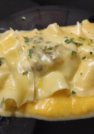 Una foto de Raviolis de wonton rellenos de langostinos, chalota y puerro con crema de calabaza asada