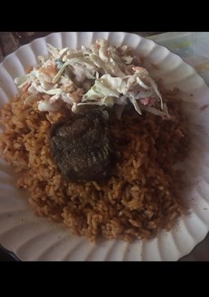 A picture of Jollof rice with beef and salad.