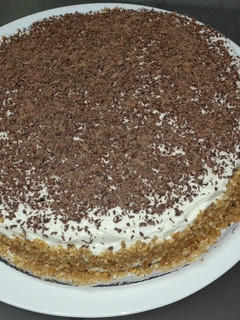 Una foto de Bizcocho relleno de trufa y cobertura de nata con escamas de chocolate