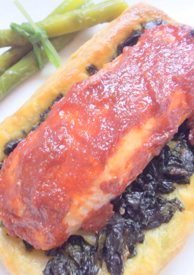 Una foto de Salmón con salsa roja y espinacas