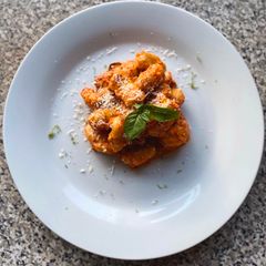 A picture of Gnocchi with charred red pepper and pistachio pesto and sautéed mushrooms.