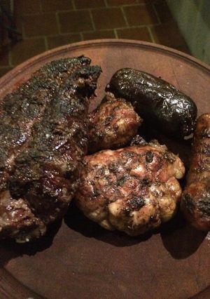 Una foto de Asado con ensalada de verdes, ensalada de cebollas ahumadas, papas al fuego y pasta de ajo 