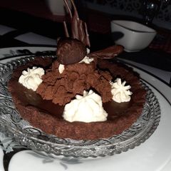 A picture of Mini chocolate tart with ganache topping and fresh cream.