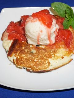 A picture of Ripe Banana Ice Cream over Pancakes with Strawberry Sauce.